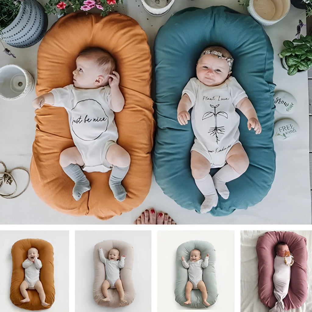 Beige portable cotton baby nest crib for infants on a neutral background.