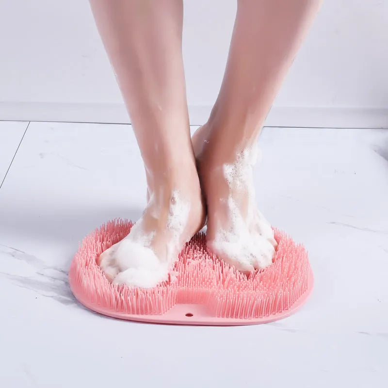 Orange massage bath brush with silicone bristles and suction cup base on a shower floor