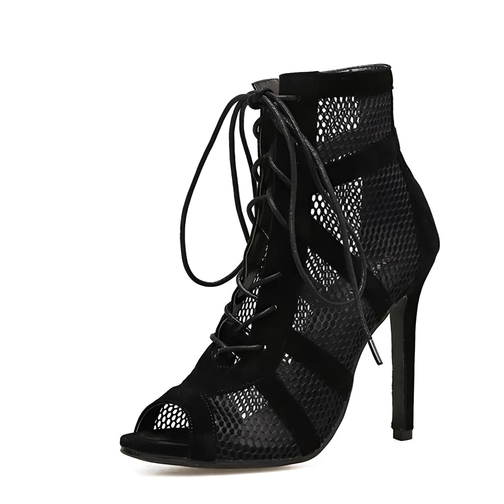 Black suede women's lace-up high heel shoes with a tall heel on a wooden floor.