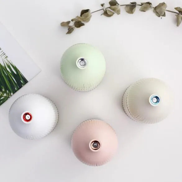White ultrasonic aromatherapy diffuser and humidifier with LED light on a wooden surface
