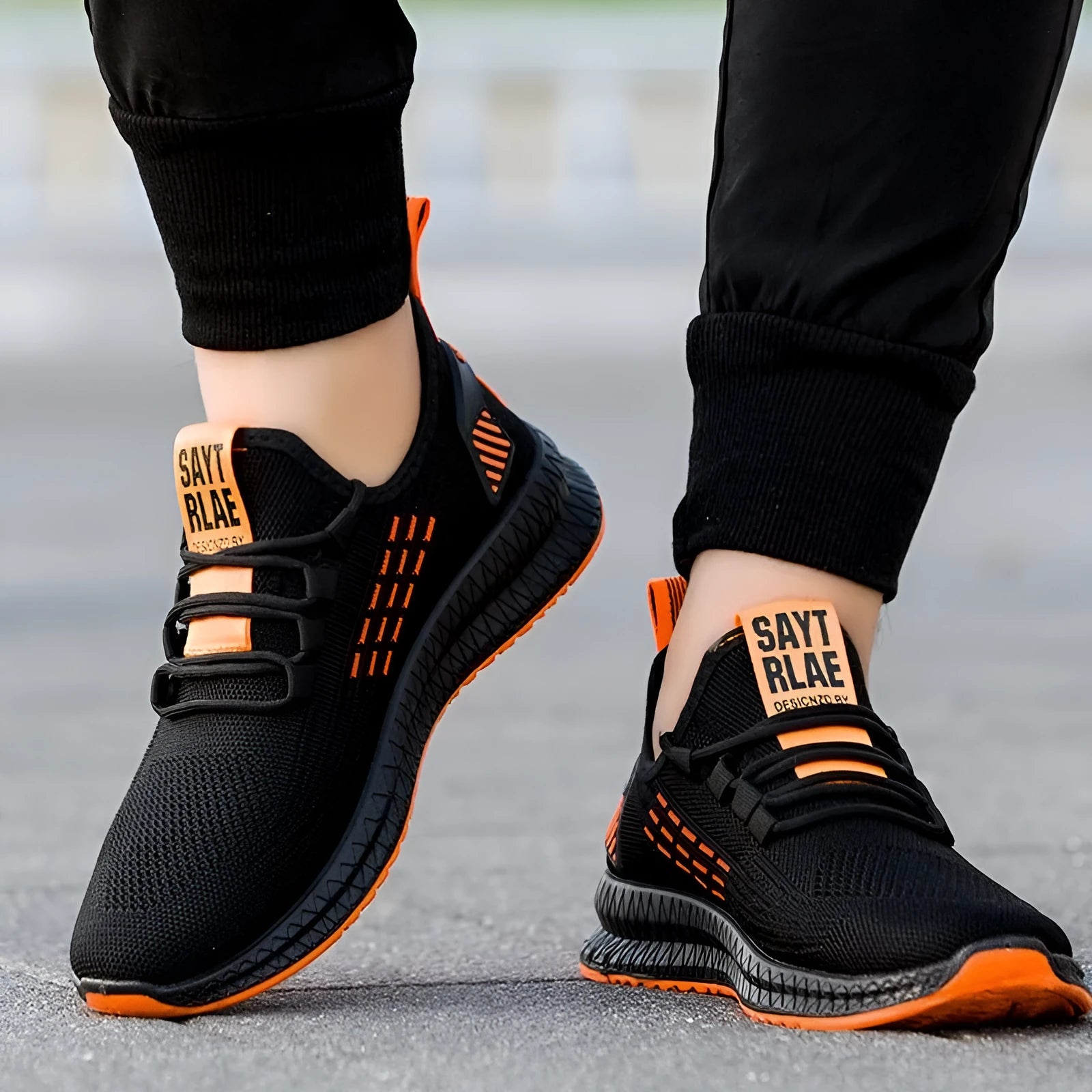 Men's black low-top casual sneakers with flying weave upper and cross strap detail on a white background.