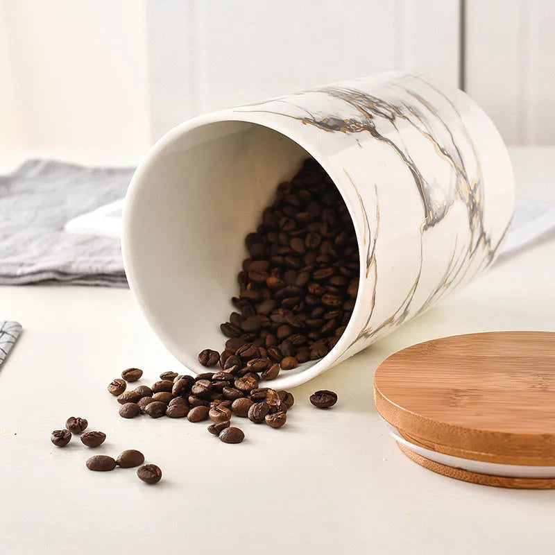 Three marbled ceramic jars with bamboo lids in large, medium and small sizes on a kitchen counter