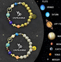 Two natural stone beaded bracelets with zodiac designs on a wooden surface