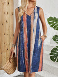 A woman wearing a v-neck sleeveless dress with colour block stripes and a mid-length skirt.