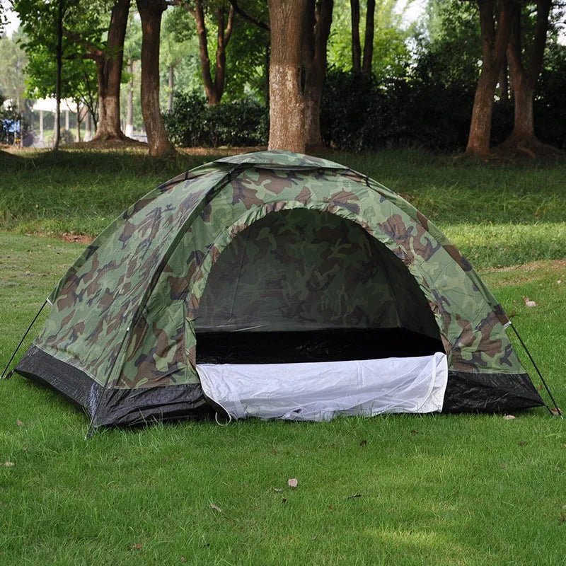 Green camouflage two-person dome tent with mesh panels and guylines pitched outdoors.