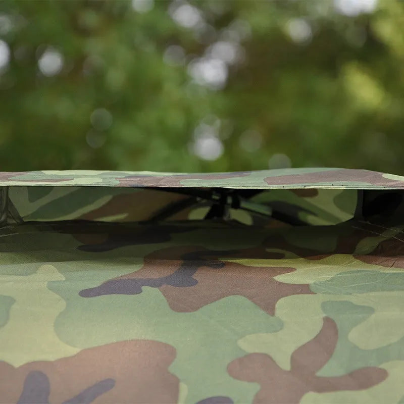 Green camouflage two-person dome tent with mesh panels and guylines pitched outdoors.