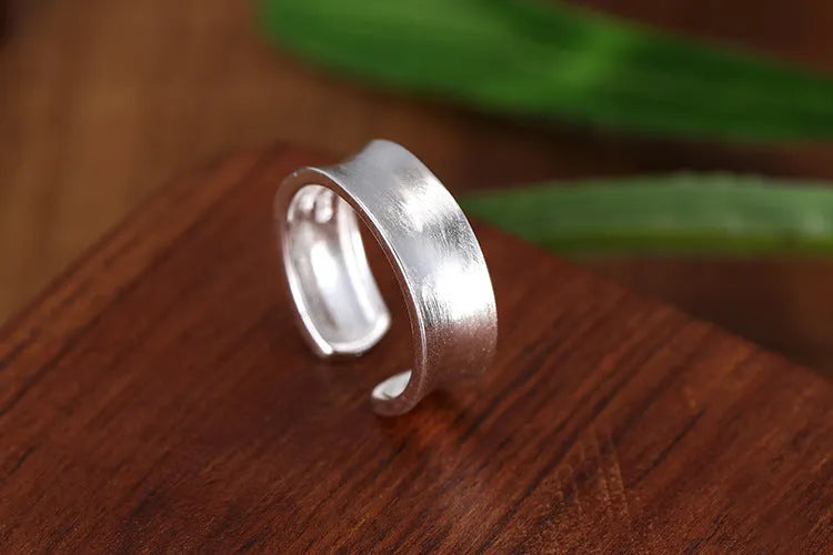 Geometric open ring in frosted sterling silver on a neutral background, showing adjustable opening.