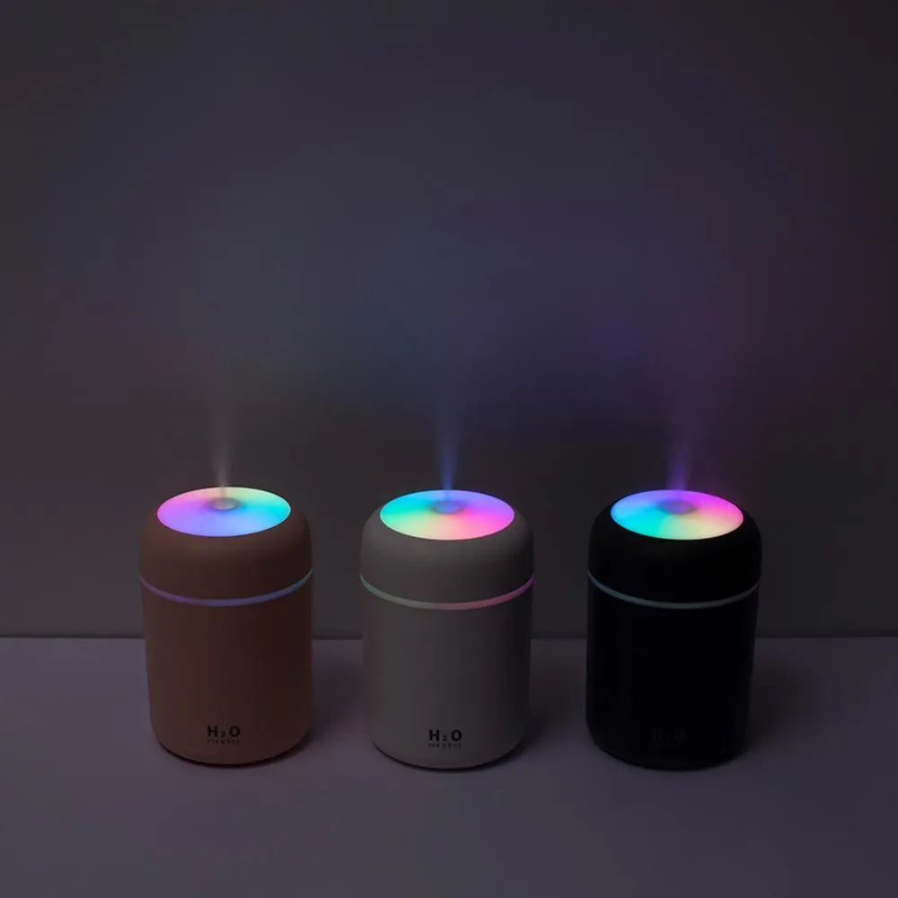 Pink USB desktop humidifier with mood lights and water tank on a wooden desk