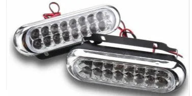 Two white car LED auxiliary lights with iron brackets and screws on a dark background