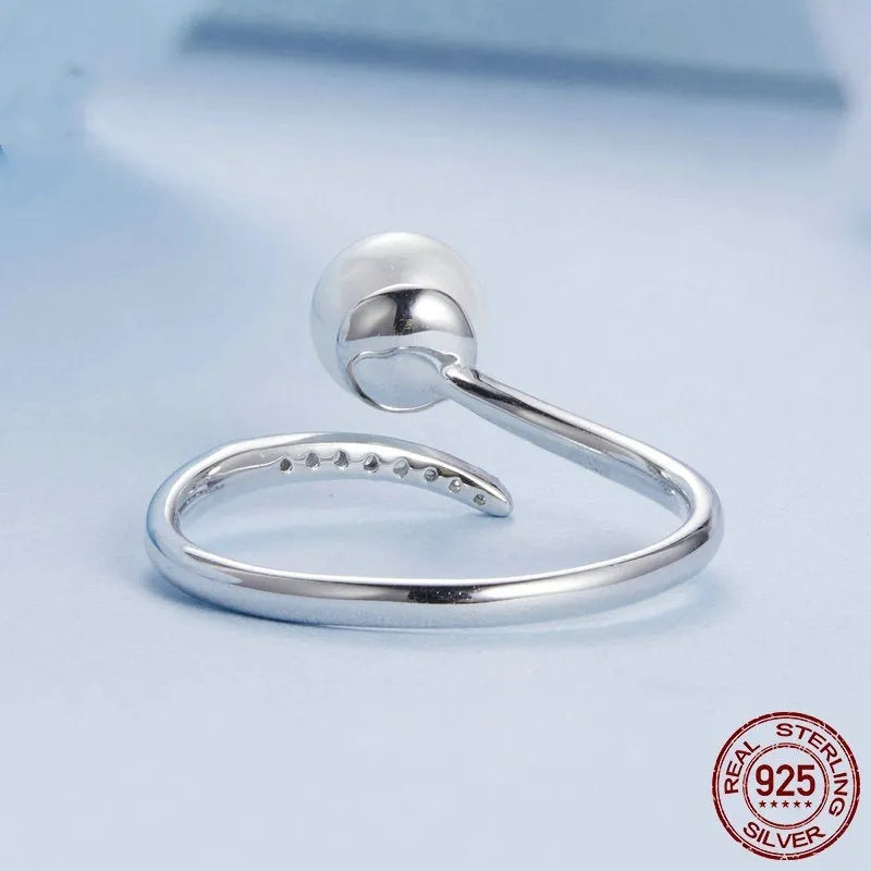 Sterling silver adjustable ring with a natural pearl on an open loop band.