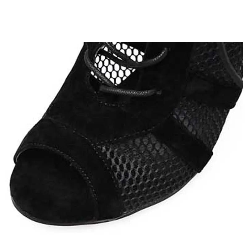 Black suede women's lace-up high heel shoes with a tall heel on a wooden floor.
