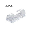 Transparent plastic self-adhesive wire holder routing snap clip on a desk surface with a white cable inserted