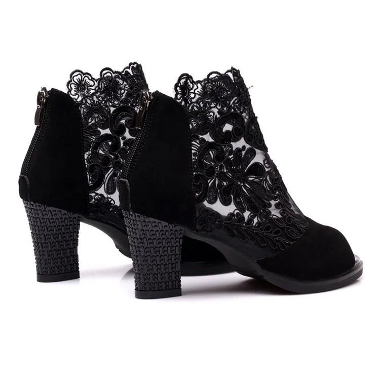 Black lace gladiator sandals with a square high heel, floral detail, and a zip closure at the ankle.