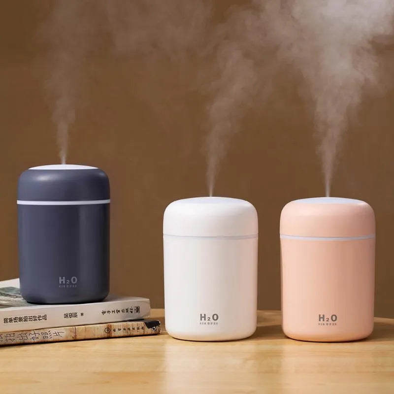 Pink USB desktop humidifier with mood lights and water tank on a wooden desk