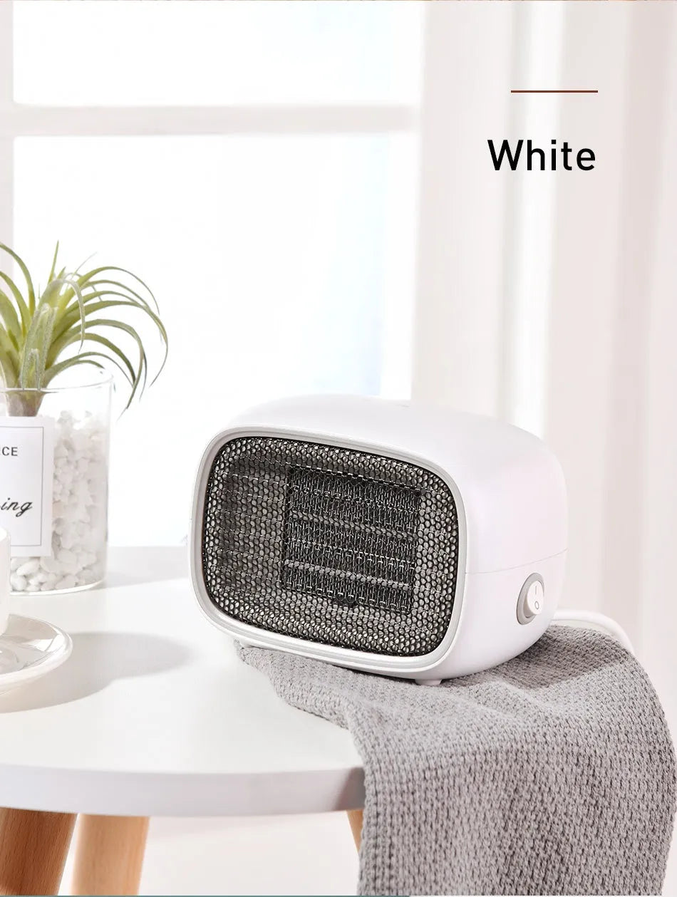 Mini green PTC ceramic fan heater on a desk showing compact size