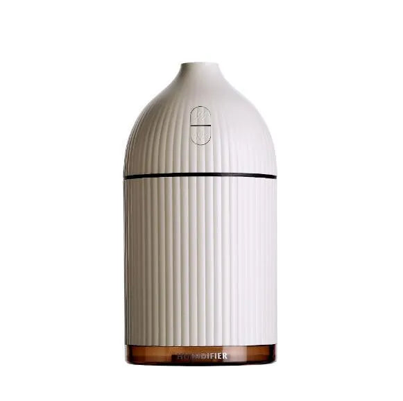 White ultrasonic aromatherapy diffuser and humidifier with LED light on a wooden surface