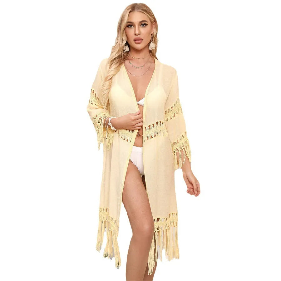 Yellow hand-crocheted women's beach cardigan with tassel trim on a hanger