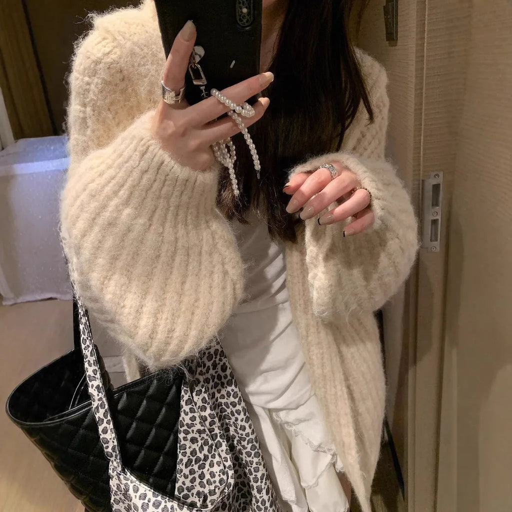 A woman wearing a thick, dark grey hooded cardigan with a loose fit and regular sleeves.