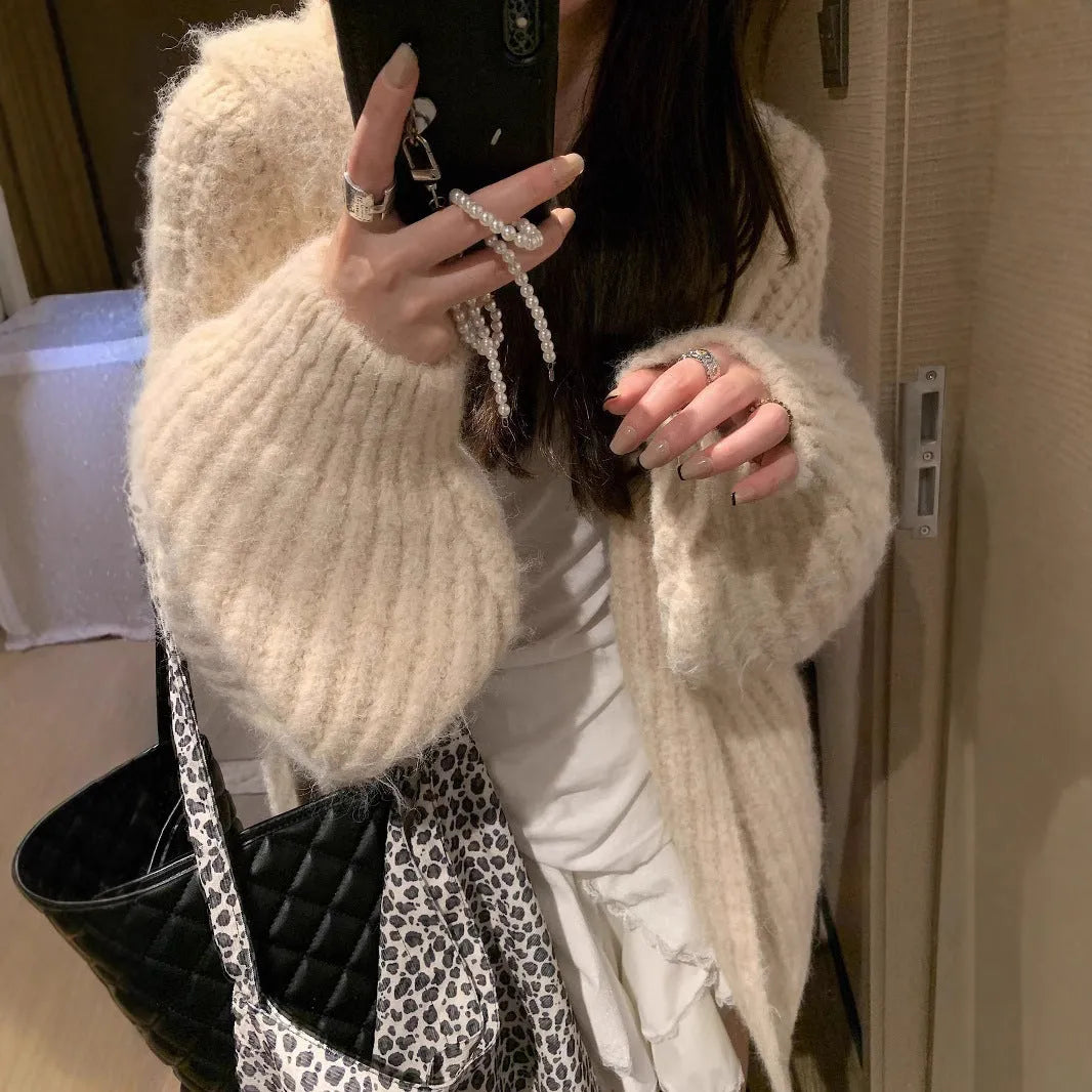 A woman wearing a thick, dark grey hooded cardigan with a loose fit and regular sleeves.