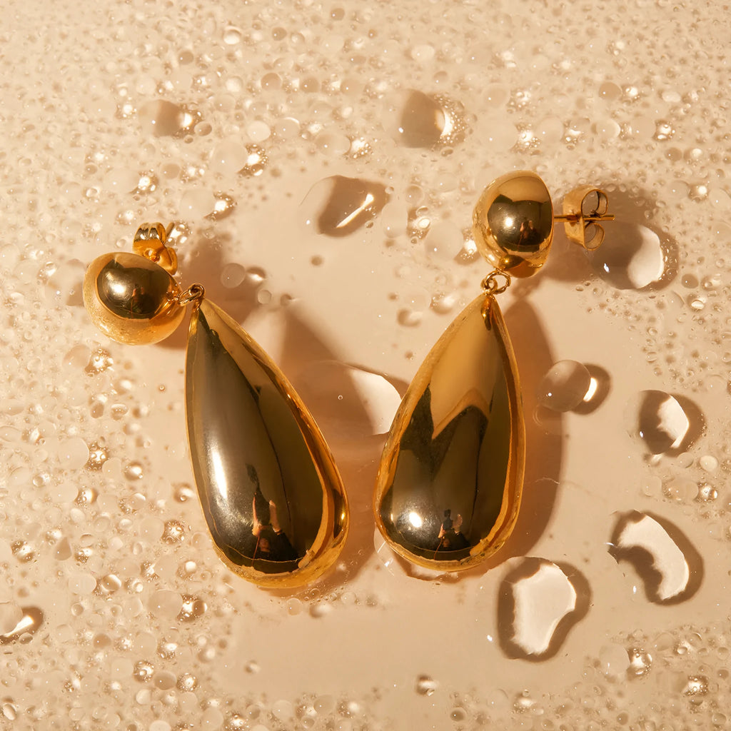 Gold electroplated stainless steel earrings with a geometric hemisphere and water drop pendant.