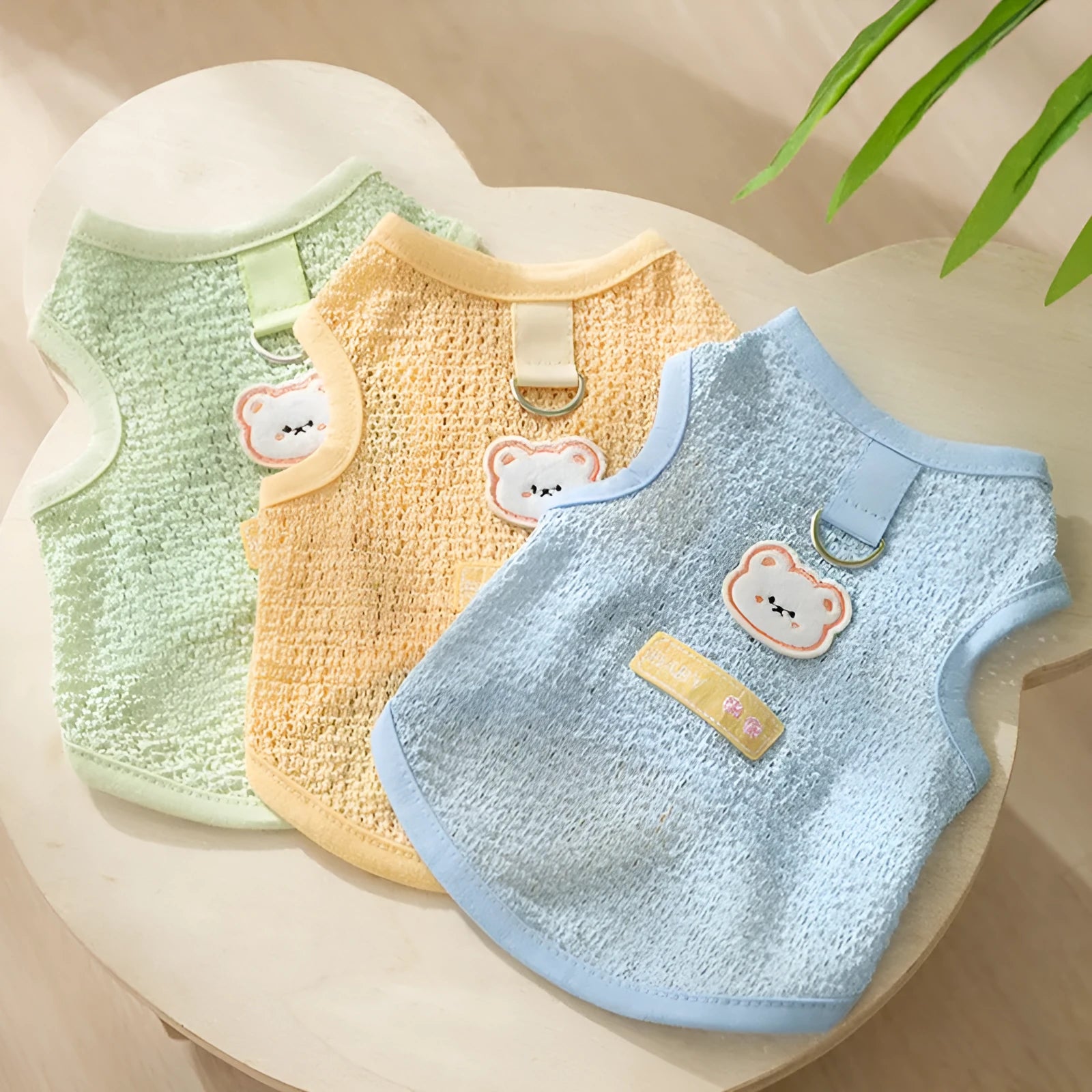 Green cat clothing with a cartoon bear patch, made from hollowed-out knitted fabric.