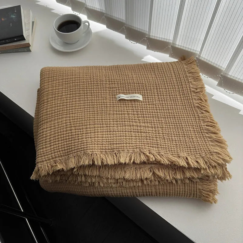 Four-layer gauze cotton blanket with tassel trim in navy blue colour laid flat