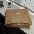 Four-layer gauze cotton blanket with tassel trim in navy blue colour laid flat