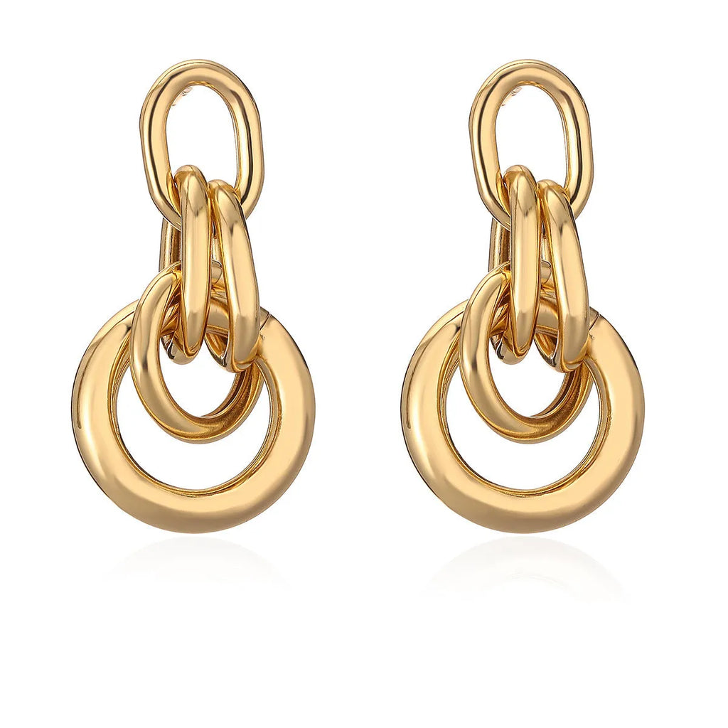 A pair of gold geometric drop earrings with an irregular asymmetric shape, made from copper.