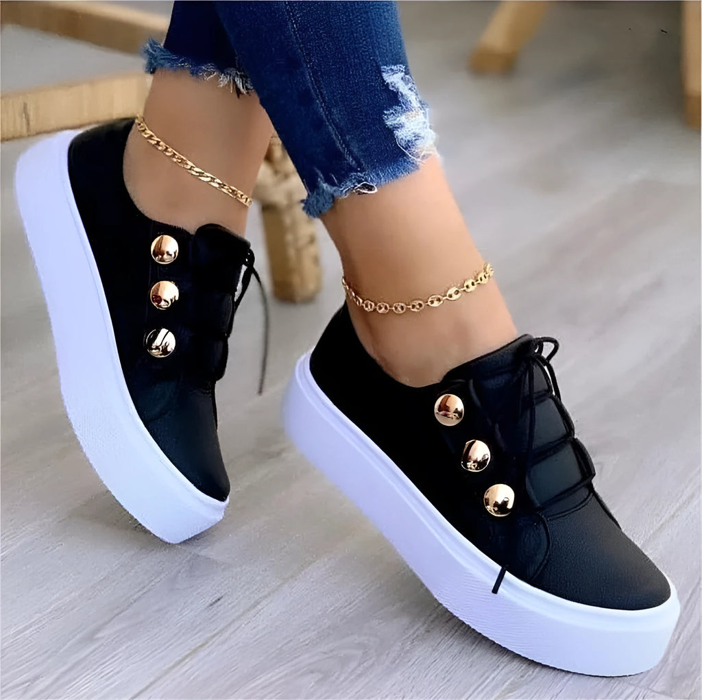 Women's white lace-up flats sneakers with rivet detail on the side and round toe.