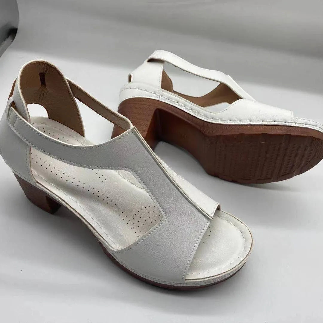 Women's white peep toe wedge sandals with a Roman-style buckle strap and low heel.