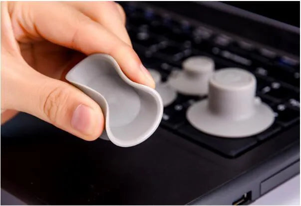 Four grey plastic non-slip laptop cooling pads, two large and two small, on a desk.