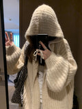 A woman wearing a thick, dark grey hooded cardigan with a loose fit and regular sleeves.
