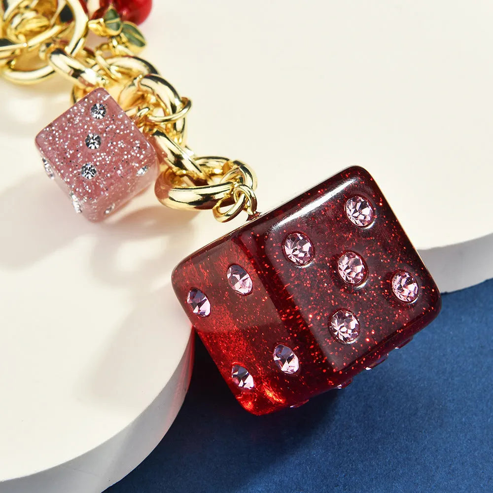 Square metal keychain pendant with a vintage red and white cherry dice pattern.
