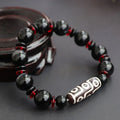 Hand-woven black agate Dzi bead bracelet with 11mm geometric beads on a wrist
