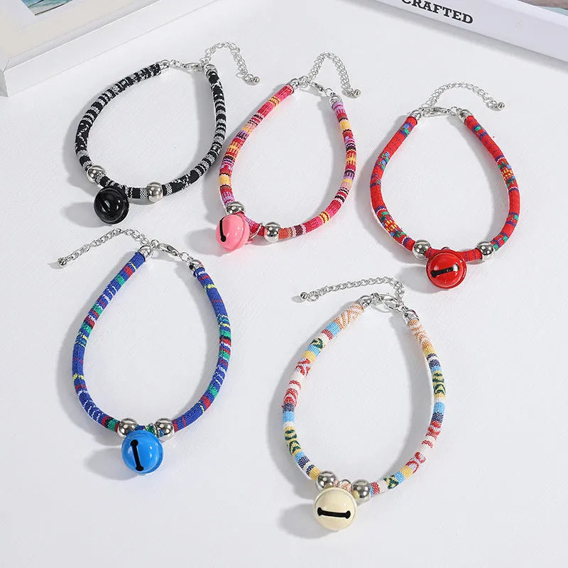 Colourful adjustable pet collar with ethnic patterns and a small metal bell attached, shown in multiple colour options.