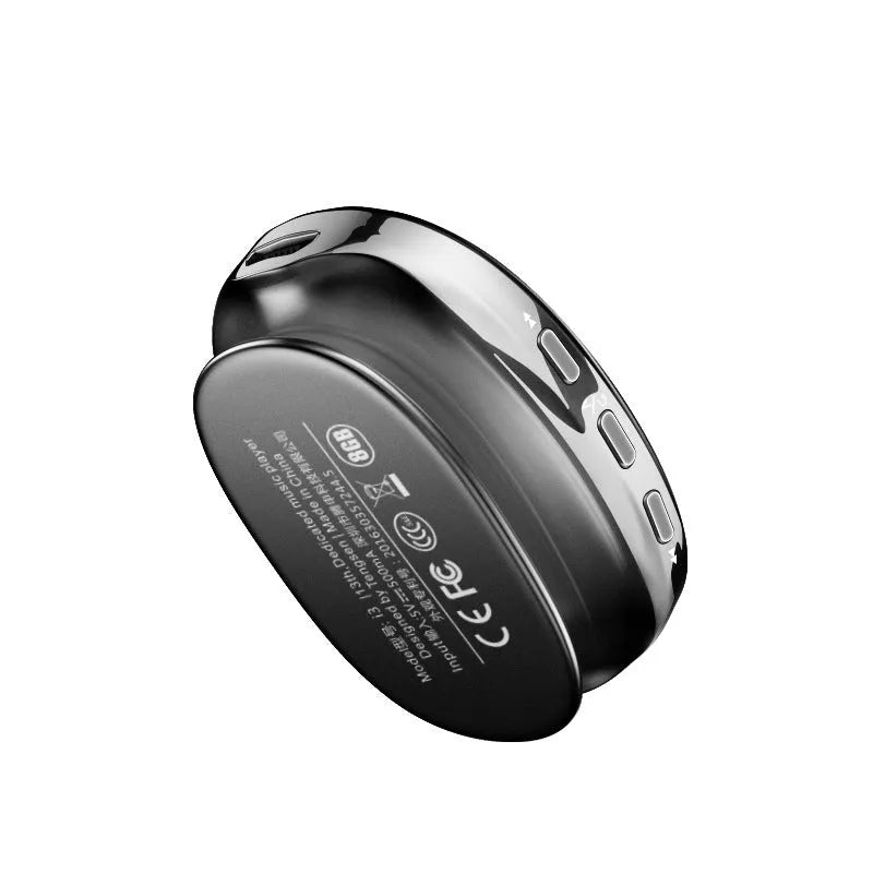 A compact black Bluetooth MP4 music player with an OLED screen showing track info, placed next to wired headphones.