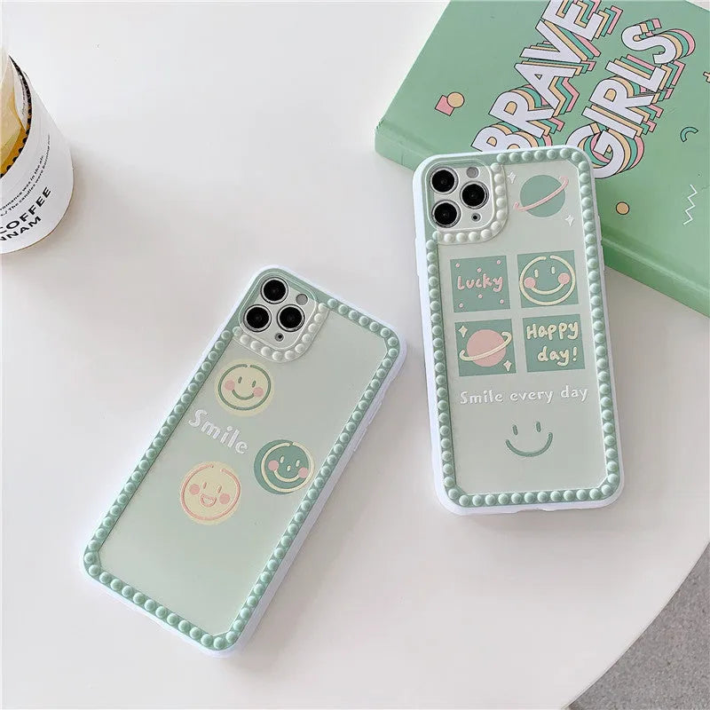 Green TPU iPhone case with geometric smiley face and polka dot design on a table.