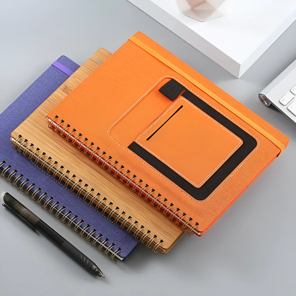 Open erasable coil notebook with stone paper pages, a pen, and a wipe cloth on a desk.
