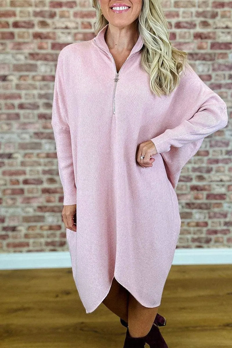 A woman wearing a solid colour loose knitted dress with raglan sleeves, shown in one of five available colours.