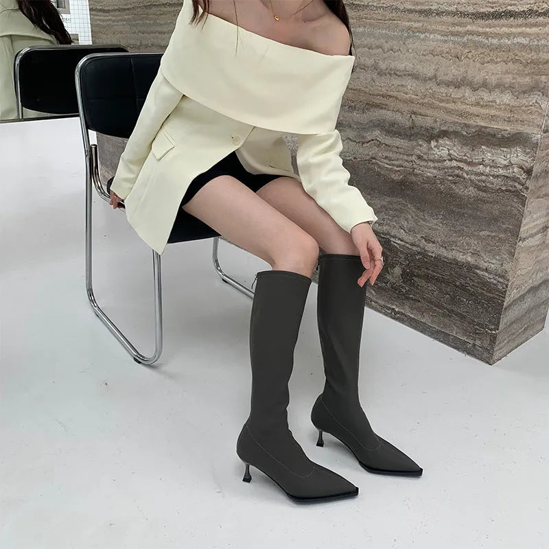 Black pointed toe women's below knee stiletto boots with a back zipper closure.
