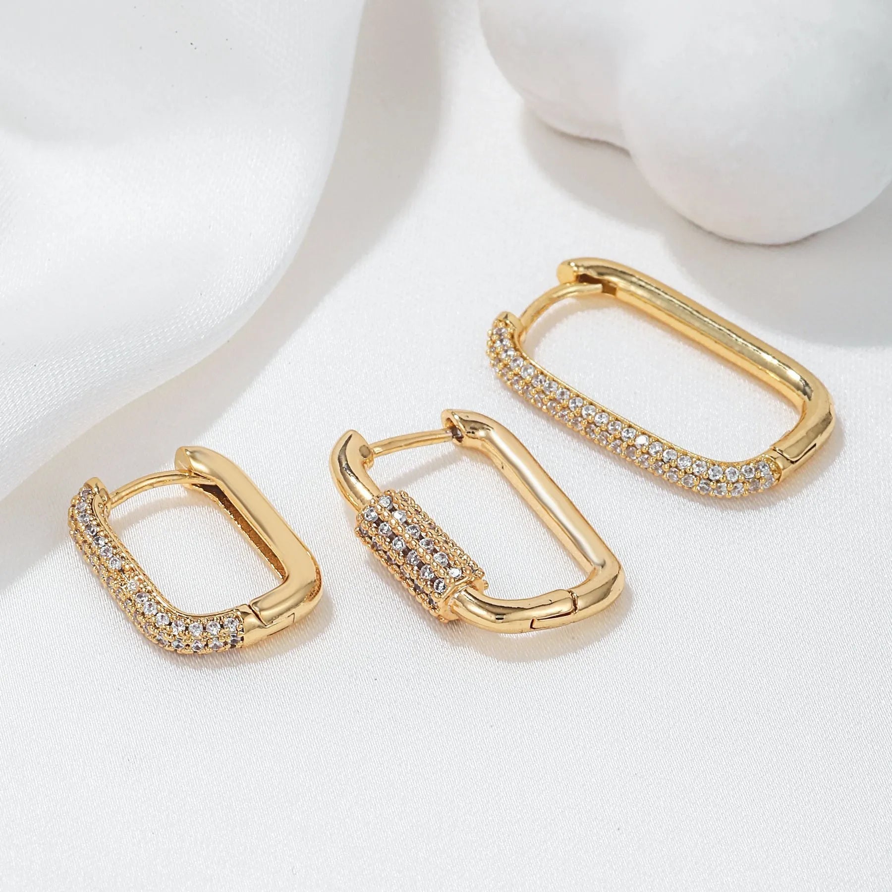 Three geometric ear clips with micro inlaid zircon detailing on copper in gold and white colours