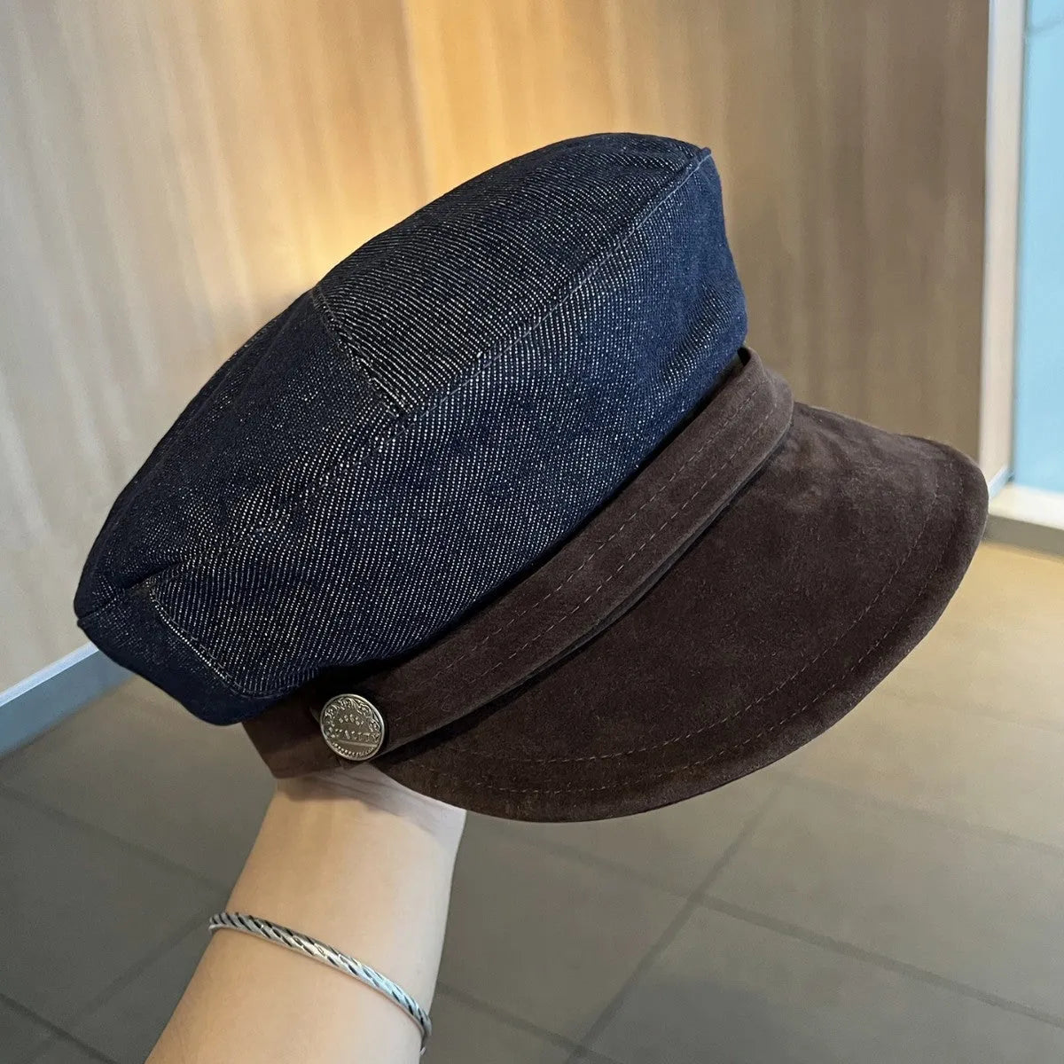 Adjustable octagonal denim newsboy hat in dark blue with contrast brim on white background