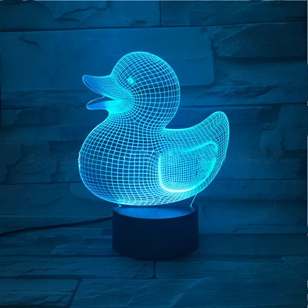 Little yellow duck 3D night light with remote control on a table, showing colourful LED illumination.