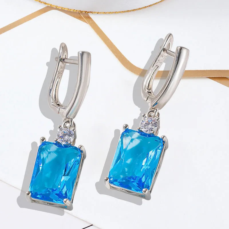 A pair of square gold and silver electroplated copper earrings showing geometric quadrilateral shape.