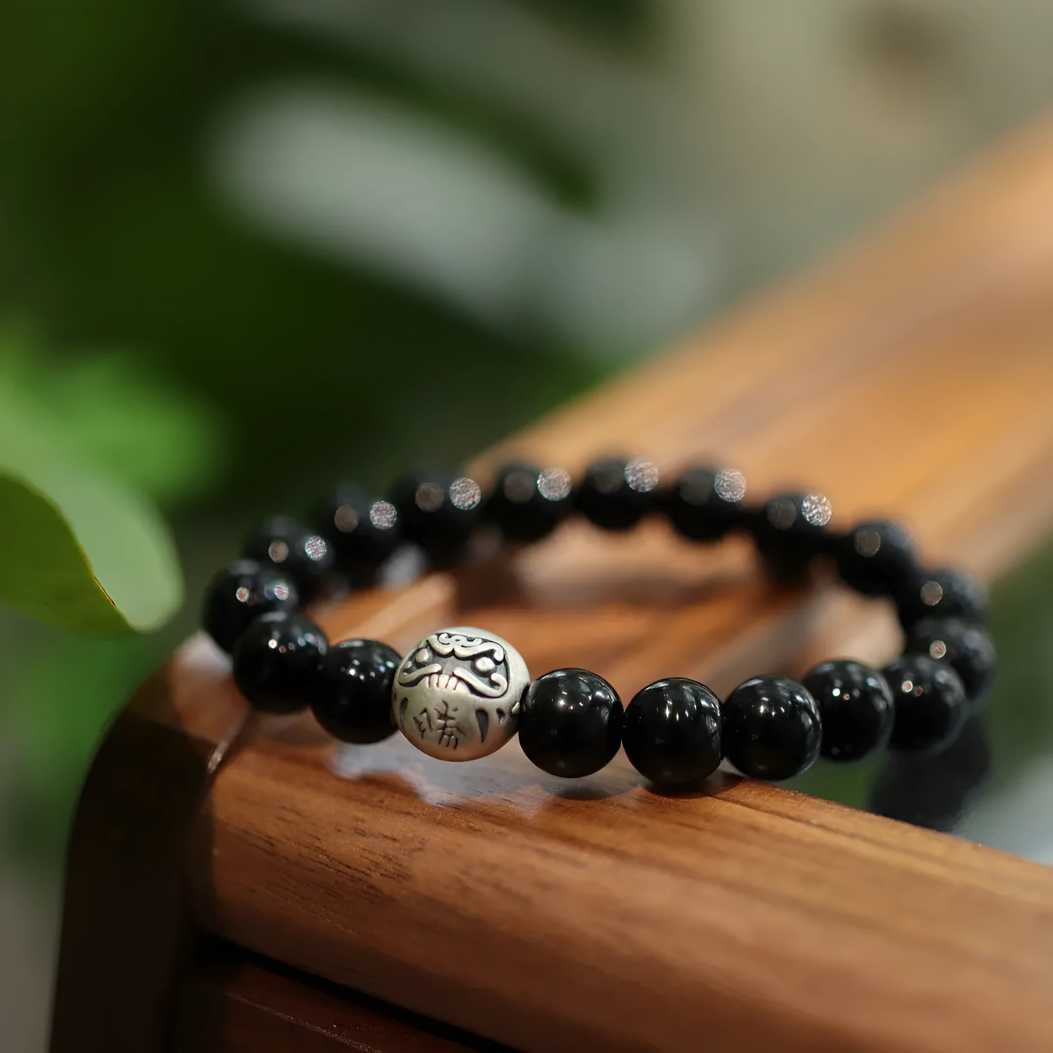 Close-up of a black agate and sterling silver bracelet with 10mm beads and Chinese style design.