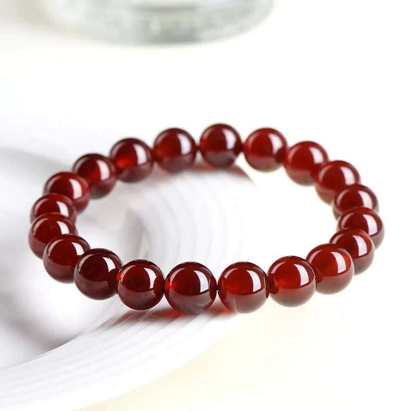 Natural orange red garnet ball bracelet with Ruyi elements on a wrist, showing retro unisex design.