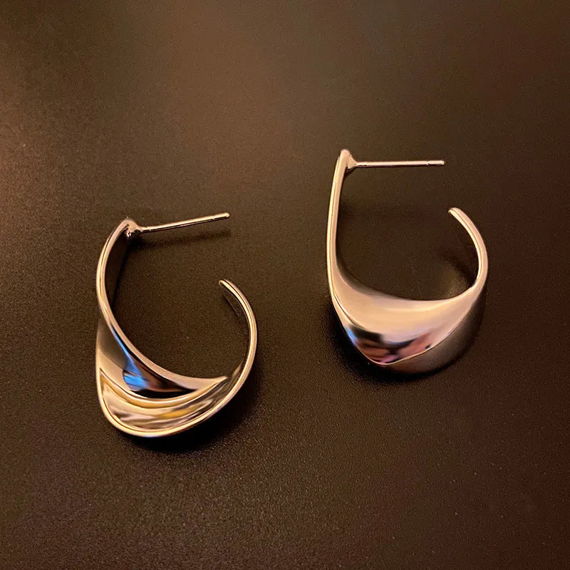 Geometric twisted metal earrings with electroplated gold or silver finish and round design elements