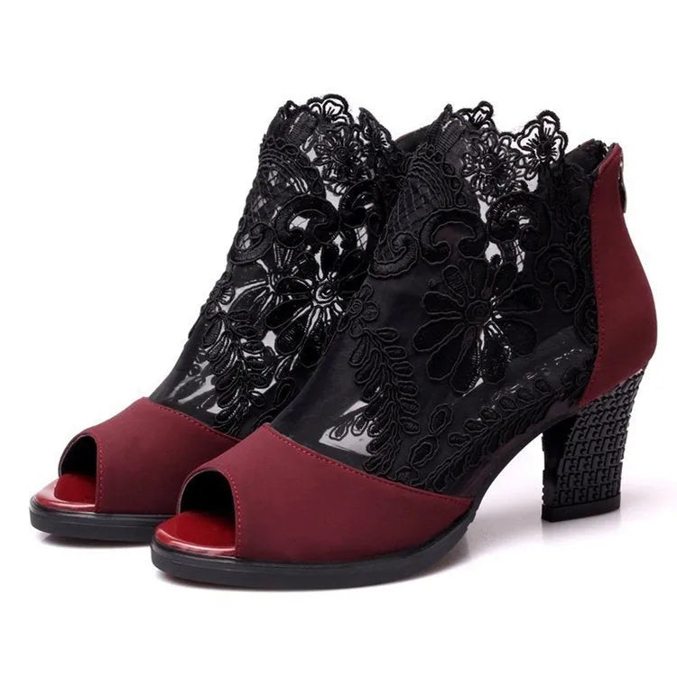 Black lace gladiator sandals with a square high heel, floral detail, and a zip closure at the ankle.
