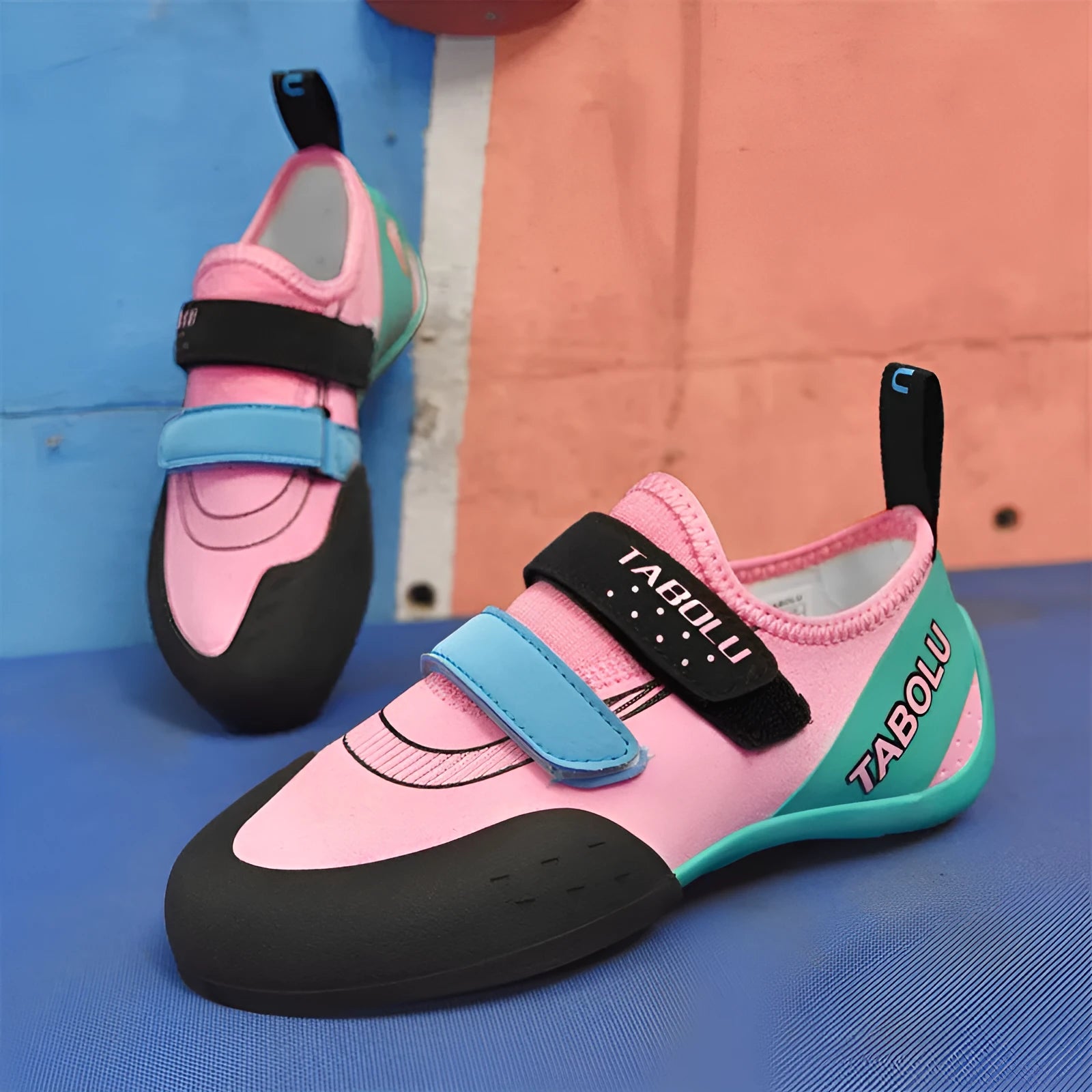 A pair of beginner rock climbing shoes with a velcro strap, shown in a black and red colour combination.