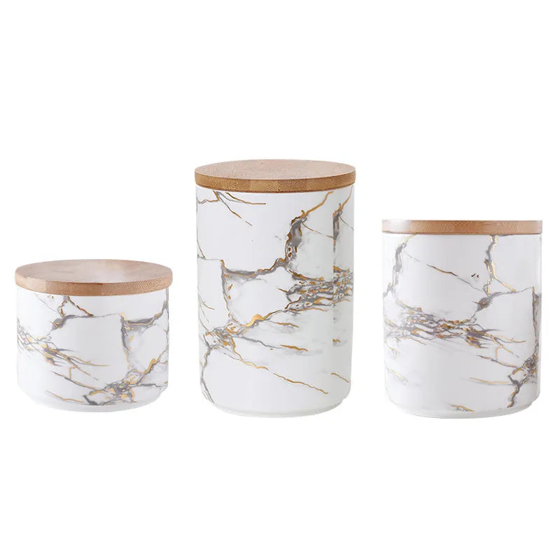 Three marbled ceramic jars with bamboo lids in large, medium and small sizes on a kitchen counter